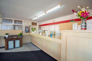 a lobby with a counter with a vase of flowers at The Midcity Motor Lodge in Orange