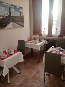 una sala da pranzo con tavoli e sedie bianchi e un dipinto di Residence Tucci ad Ascoli Piceno