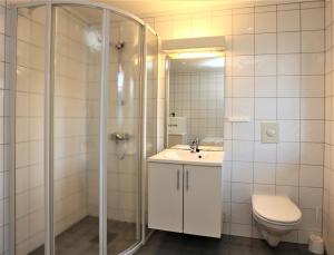 a bathroom with a shower and a sink and a toilet at Beverøya Hytteutleie og Camping in Bø