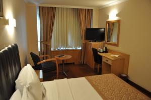 アダナにあるSurmeli Adana Hotelのベッド、デスク、テレビが備わるホテルルームです。