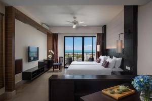a large hotel room with a bed and a television at Ramada Plaza by Wyndham Sanya Bay in Sanya