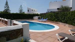 Una piscina con dos sillas de jardín junto a una pared. en Villa Na y Veni, en Cala'n Bosch