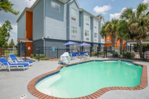 uma piscina num hotel com cadeiras e um edifício em Trident Inn & Suites, Baton Rouge em Baton Rouge