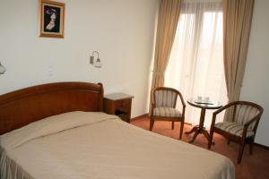 a bedroom with a bed and two chairs and a table at Hotel Sarmis in Deva