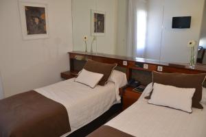 a hotel room with two beds and a mirror at Hotel de la Cañada in Córdoba