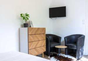 a bedroom with two black chairs and a tv at Studio calme, lumineux, terrasse, WIFI, 1.5 Km du front de mer in Saint-Nazaire