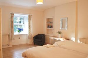 um quarto com uma cama, uma cadeira e uma janela em Little Dunbar Cottage em Kirkbean