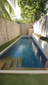 una piscina en un patio trasero con una valla de madera en Treetop Suites en Corón