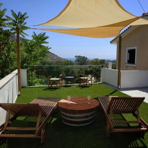 eine Terrasse mit einem Tisch, 2 Stühlen und einem Sonnenschirm in der Unterkunft Kykeon Studios in Kateliós