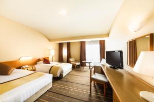 a hotel room with two beds and a television at Senri Hankyu Hotel Osaka in Toyonaka