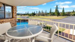 a balcony with a table and chairs and a pool at Beach Point - East Ballina in East Ballina