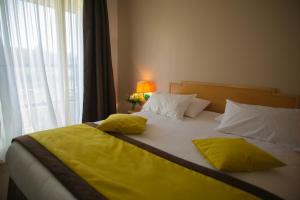 Cama con sábanas amarillas y almohadas junto a una ventana en Golf Hotel de Mont Griffon, en Luzarches