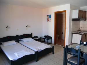 1 dormitorio con 2 camas y cocina con fregadero en Pension Eleni Studios, en Kokkari