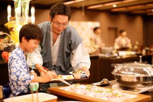 Ein Mann und ein Junge in einer Küche, die Essen zubereiten. in der Unterkunft Hotel Senshukaku in Hanamaki