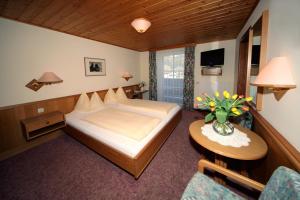 a bedroom with a bed and a table with a vase of flowers at Pension Salzburger Hof in Fuschl am See