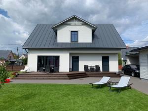 une maison blanche avec un toit noir et deux chaises dans l'établissement Pärnu Lubja Apartments, à Pärnu