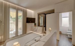 a white bedroom with a large bed and a tv at Le Palmette Suites in Cagliari