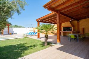 un patio con pérgola de madera, mesa y árbol en Villa Chloe, en Santa Luria