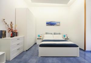 a white bedroom with a bed and a dresser at Casa Sassolini in Naples