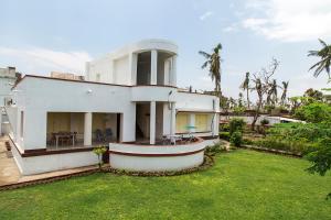 a white house with a large yard with a grass yard at Judges Court in Puri