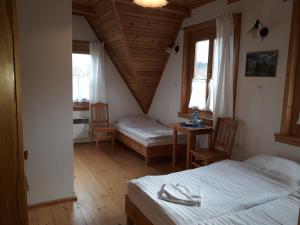 a bedroom with two beds and a table and two windows at Polana Sosny in Niedzica Zamek