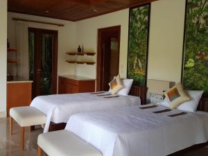 - 2 lits dans une chambre avec 2 chaises dans l'établissement The Allure Ubud Villas, à Ubud
