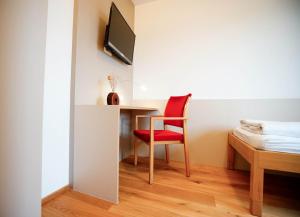 Cette chambre comprend un bureau et une chaise rouge. dans l'établissement SPES Hotel & Seminare, à Schlierbach