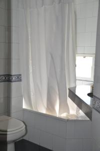 a bathroom with a toilet and a white shower curtain at Hotel de la Cañada in Córdoba