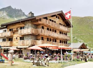 um grande edifício com pessoas sentadas fora dele em Hotel Alpina em Fiesch