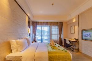 a hotel room with a large bed with a teddy bear on it at YueXin Tomorrow Hotel Sanya in Sanya