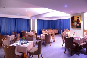 a dining room with tables and chairs and blue curtains at Juffair Gate Hotel in Manama