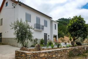 una casa blanca con una pared de piedra delante de ella en Casa do Ferreiro II en Góis