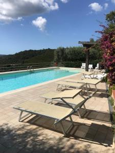 a group of lounge chairs next to a swimming pool at Residence Le Solane in Marina di Campo
