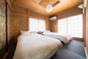 two beds in a room with two windows at K&K Jujo House in Tokyo