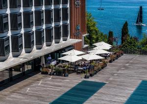 a row of tables with white umbrellas next to a building at Lake Geneva Hotel in Versoix