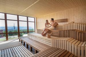 Ein Mann und eine Frau sitzen in einer Sauna in der Unterkunft Grand Hotel BELLEVUE in Starý Smokovec