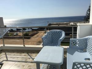 two blue chairs sitting on a balcony overlooking the ocean at Arabesque Style - 2 appartements in Kelibia