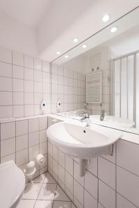 ein weißes Badezimmer mit Waschbecken und Toilette in der Unterkunft Baltic Zinnowitz - Hotel mit Meerwasserpool und Thermalbad in Zinnowitz