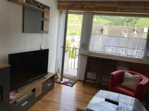 a living room with a flat screen tv and a red chair at Beim Winzer in Zell an der Mosel