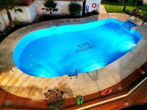 Skats uz peldbaseinu naktsmītnē Apartamento con piscina a 150 metros playa Netflix P Video Aire Acondicionado calefacción toallas y sillas playa sombrilla 2 terrazas una sobre piscina centro ciudad 1 Smart TV por habitación vai tās tuvumā