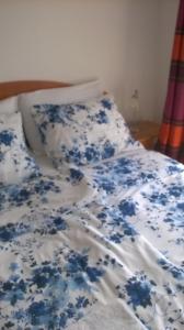 Cama con sábanas y almohadas azules y blancas en L&L Apartments, en Povile