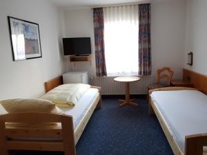 a hotel room with two beds and a tv at Smarthotel Gallmersgarten in Gallmersgarten