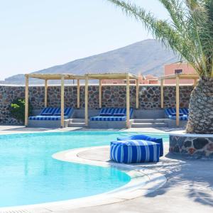 a swimming pool with blue chairs and a palm tree at Anemomilos in Oia