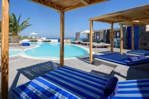 uma piscina com espreguiçadeiras azuis e um resort em Anemomilos em Oia