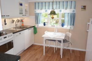 a kitchen with a table and a sink and a window at Idyllisk feriested in Røyksund
