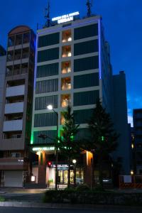 a tall building with green lights on top of it at Green Hill Hotel Urban in Kobe