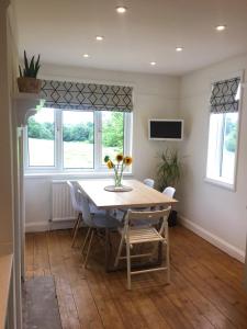 a dining room with a table and chairs and windows at The Cornish Retreat in Bude