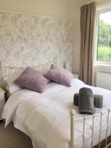 a white bed with purple pillows and a window at The Cornish Retreat in Bude