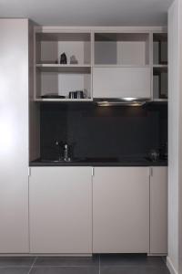 una cocina con armarios blancos y fregadero en Azur Suites, en Atenas