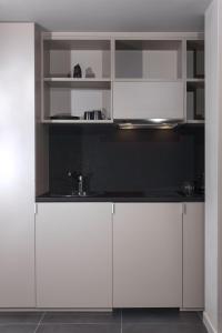 a kitchen with white cabinets and a sink at Azur Suites in Athens